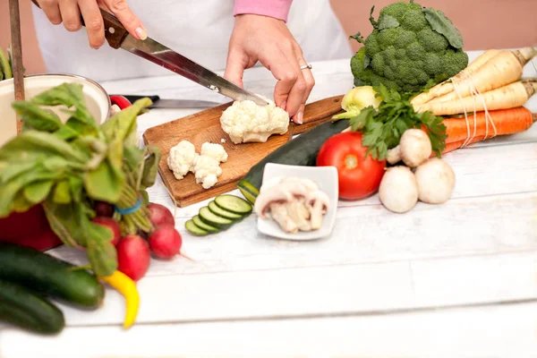 Woman cutting and preparing fresh cauliflower for cooking — Stock Photo, Image
