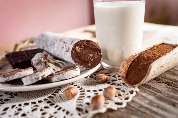 Salchicha de chocolate en plato con avellanas, cacao en cucharada de madera —  Fotos de Stock