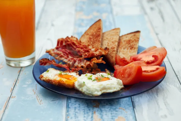 Frühstück mit Spiegeleiern, Speck, Tomaten und Toast — Stockfoto