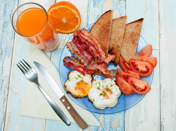 Смажені яйця з тостами, беконом і помідорами на тарілці — стокове фото