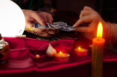 Falcı kadın başka bir kadına tarot kartı veriyor.