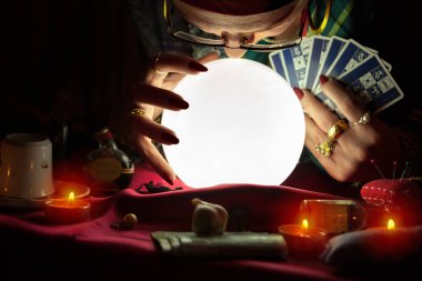 Yaşlı kristal top bakarak ve tarot kartları tutan kadın