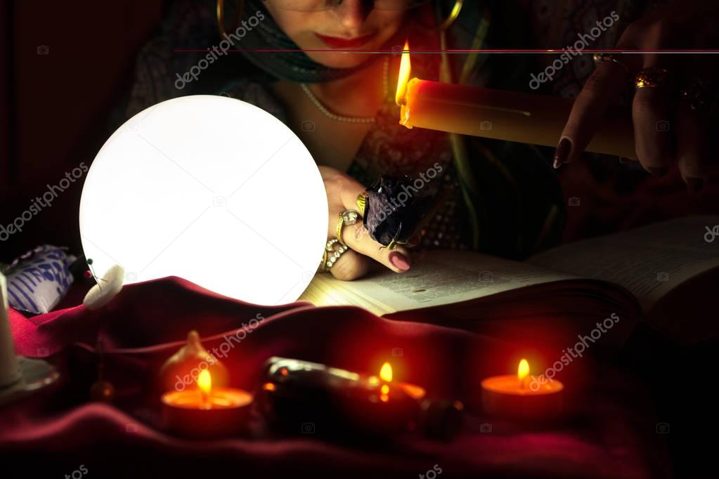 Gypsy fortune teller with burning candle and black rose