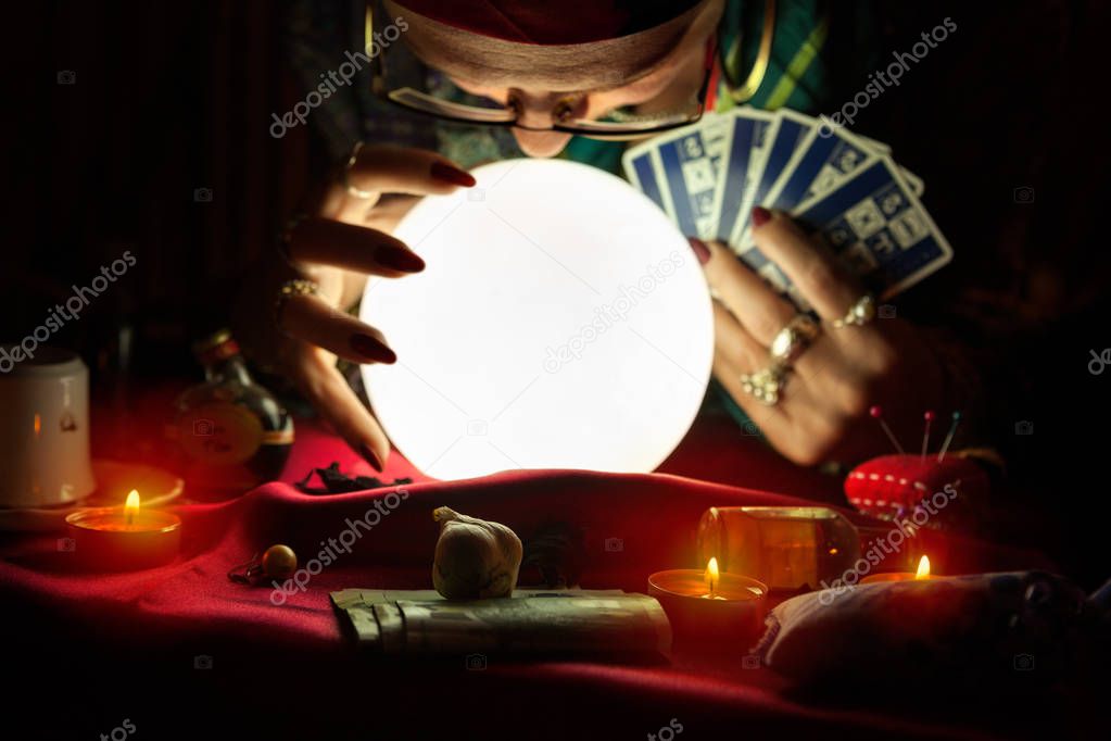 Gypsy woman looking at crystal ball and holding a tarot cards