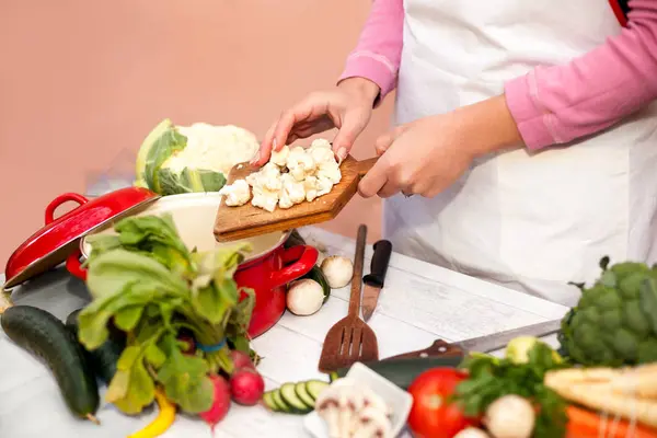 Mujer poniendo coliflor cruda en el plato de la cocina —  Fotos de Stock