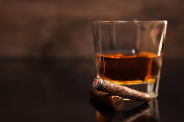 व्हिस्कीच्या ग्लासच्या बाजूला सिगार धूम्रपान करणे — स्टॉक फोटो, इमेज