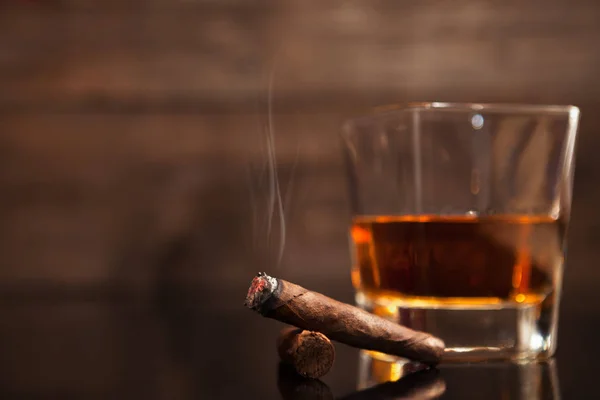 Szivar dohányzás és üveg whiskey-t a háttérben — Stock Fotó