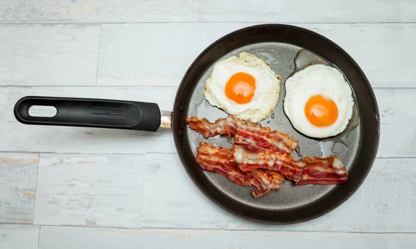 Ovos e bacon em uma panela para o café da manhã — Fotografia de Stock