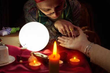 Başka bir kadın el palm okuma için tutan fortune teller kadın