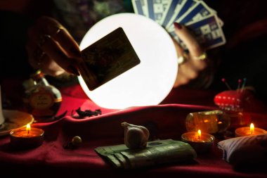 Arkasında tarot kartı ve kristal küre var.