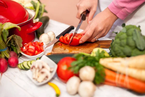Rebanadas de verduras en la tabla de cortar, mujer tomate cortado con un kni —  Fotos de Stock