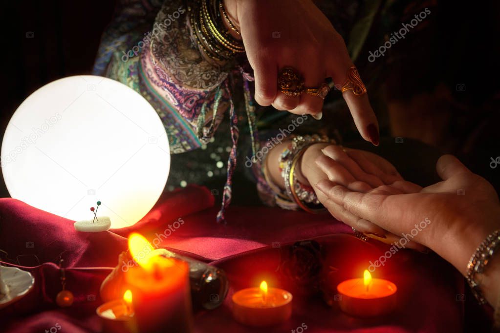 Woman fortune teller point with her finger on another woman palm