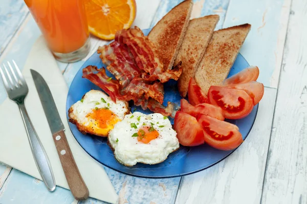 Stekt ägg, bacon, rostat bröd och tomater på tallrik — Stockfoto