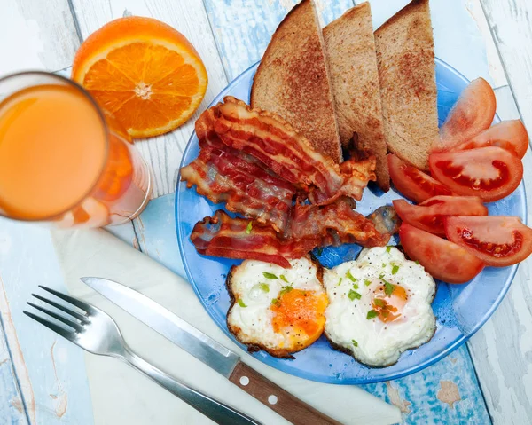 Ovanifrån av frukost med stekt ägg, bacon och tomat och oran — Stockfoto