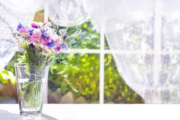 Bouquet di fiori di campo in vaso di vetro vicino alla finestra — Foto Stock