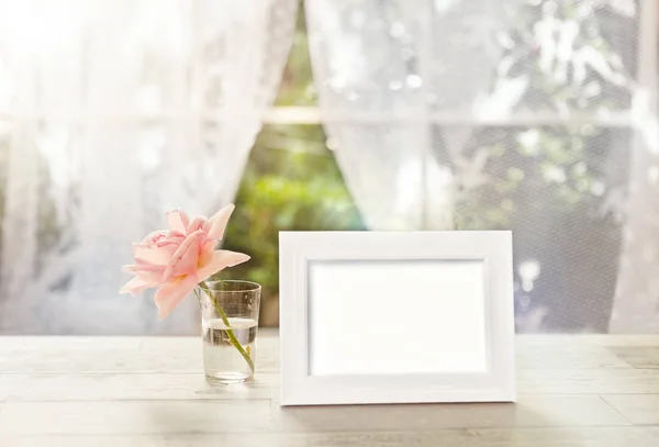 Marco blanco maqueta con rosa en vidrio — Foto de Stock