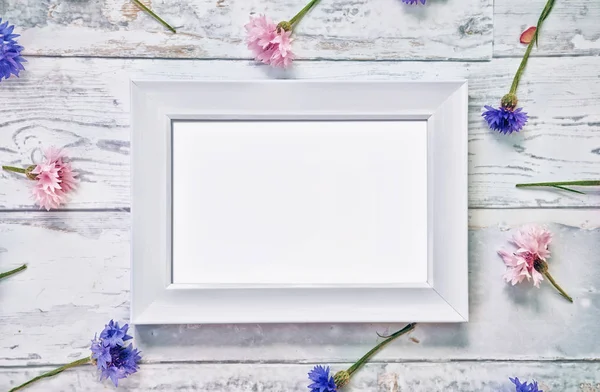 Mockup cornice bianca con fiori sul tavolo — Foto Stock