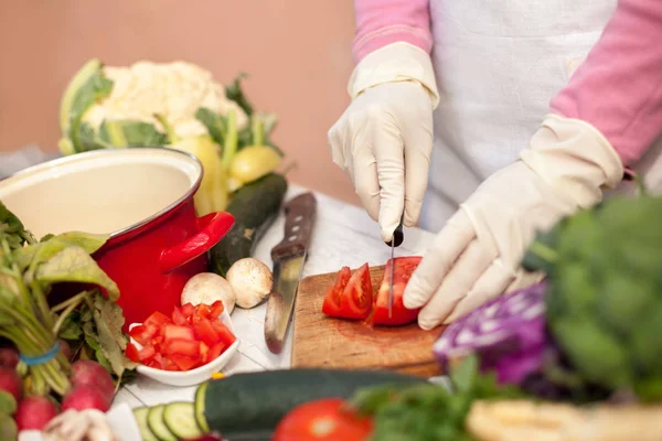 Vrouw met handschoenen snijden van tomaat — Stockfoto