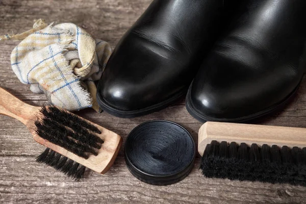 Temizlik için ahşap fırça ile siyah çizmeler