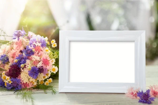 White frame and flowers on table — Stock Photo, Image