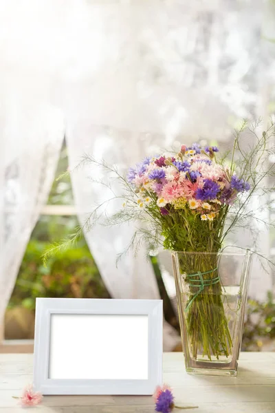 White frame and vase with flowers — Stock Photo, Image