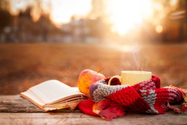 Açık kitap, apple ve sarı çay bardağı sıcak eşarp ile 