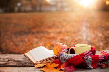 Çay bardağı sıcak eşarp açık kitap ve elma ile 