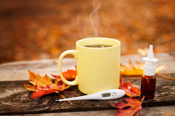 Teetasse mit Thermometer, Herbstblättern und Nasentropfen, Grippewelle — Stockfoto