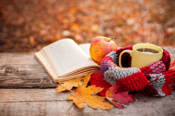 Gelbe Teetasse mit warmem Schal, aufgeschlagenem Buch und Apfel — Stockfoto