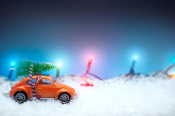 Brinquedo de carro vermelho carregando uma árvore de Natal com luzes de Natal em t — Fotografia de Stock