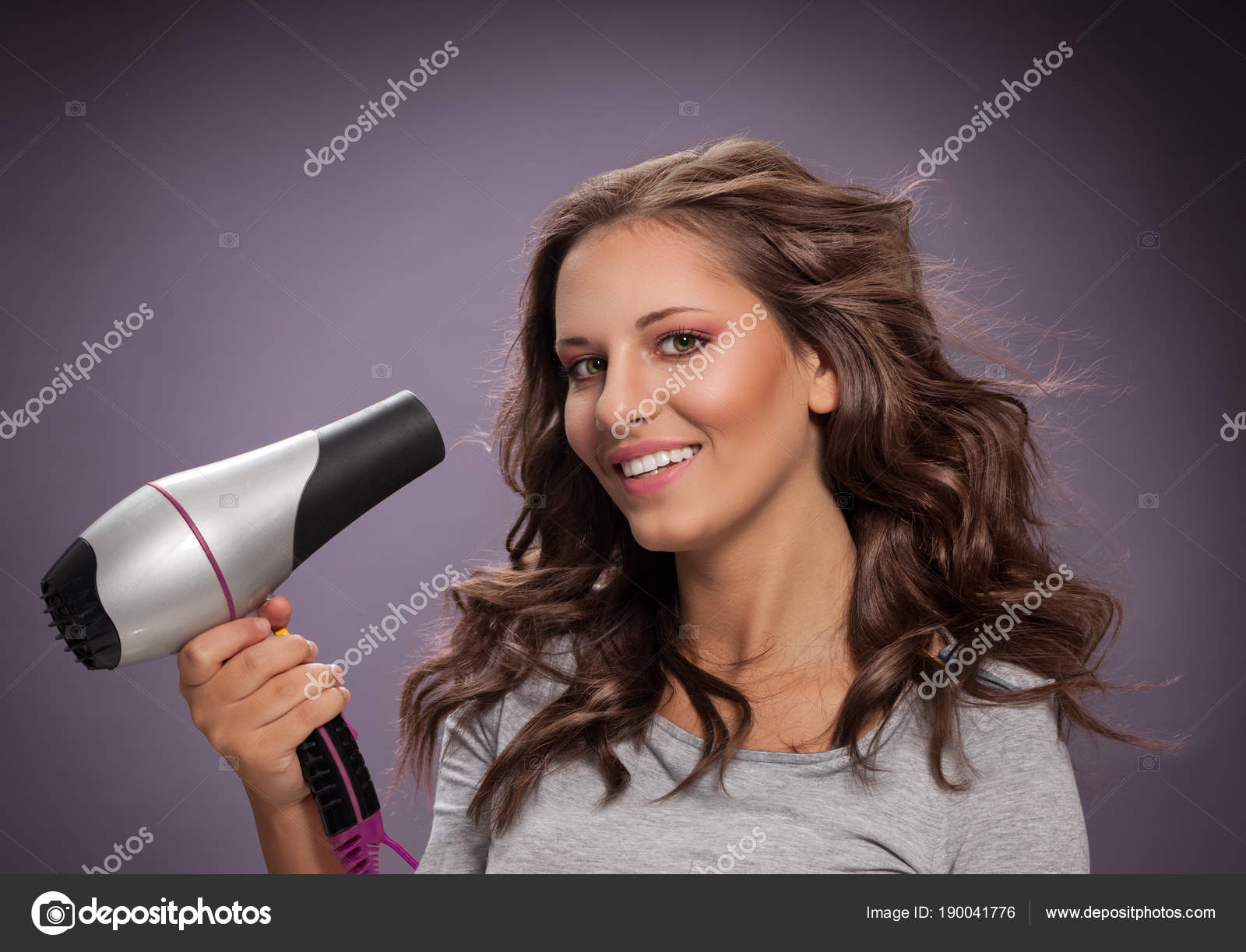Smiling Young Woman Blow Drying Her Hair Stock Photo