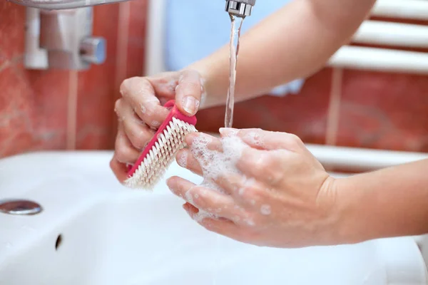 Чистящие руки с щеткой в ванной комнате — стоковое фото