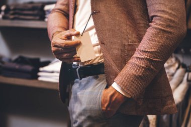 Yeni takım elbiseli adam bir etiket gösteriyor..