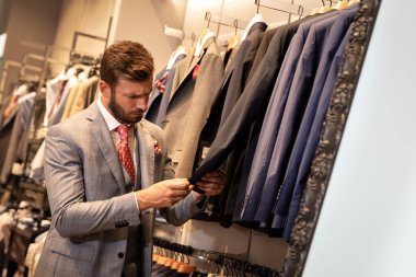 Elbise mağazasında şık bir adam var.