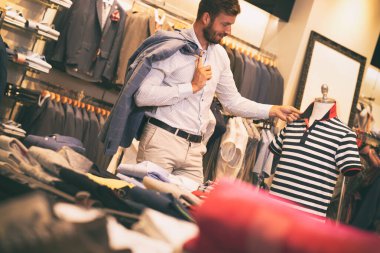 Butikte bir adam tişörte bakıyor.