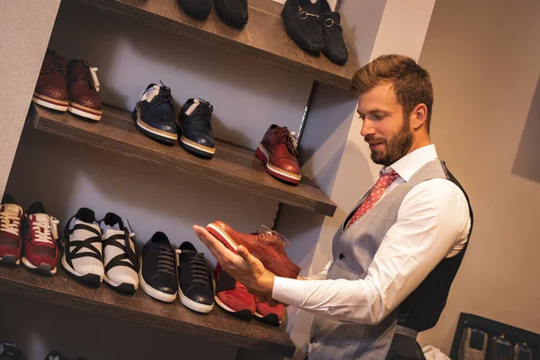 Jeune homme choisissant des chaussures élégantes dans la boutique . — Photo