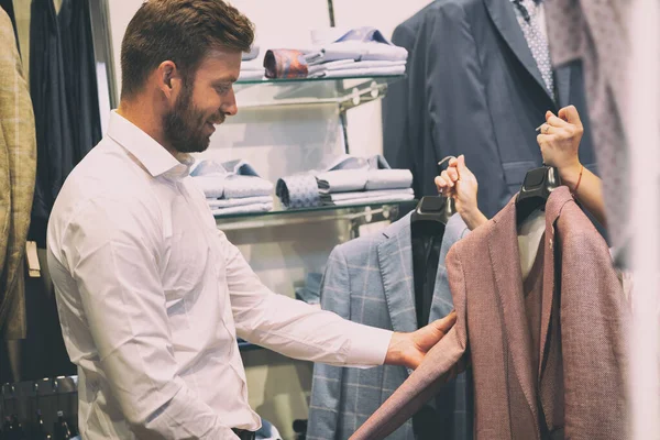 Saleswoman montre deux veste à l'homme dans le magasin de vêtements — Photo
