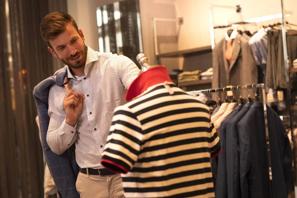 Homme souriant choisissant t-shirt au magasin de vêtements — Photo