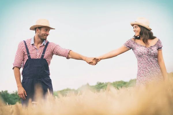 Casal de mãos dadas andando no campo de trigo — Fotografia de Stock