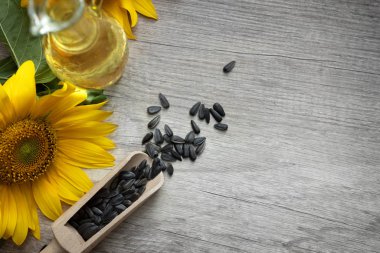 Ayçiçeği yağı, tohumlar ve çiçek açık ahşap arka planda
