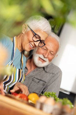 Romantik yaşlı çift birlikte oturup mutfakta yemek hazırlıyor. Ev hayatı, emeklilik, aşk