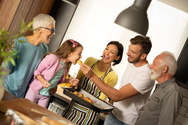 焼きたてのロールを食べるキッチンで幸せな家族 家族は一緒にパン屋を準備しています — ストック写真