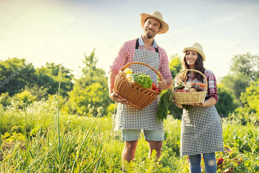 Happy owner organic farm. Smiling woman and man with baskets of healthy vegetables