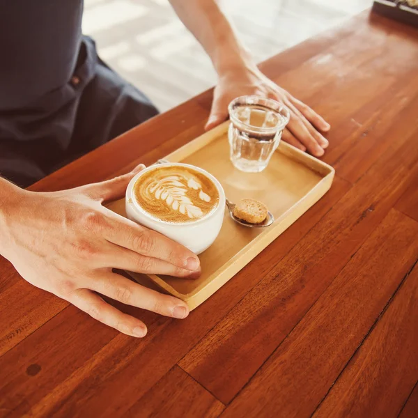 Man serverar latte på träbord — Stockfoto