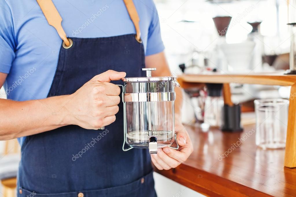 man holding french press in cafe