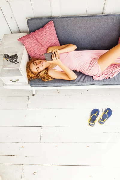 Menina relaxante no sofá com telefone — Fotografia de Stock