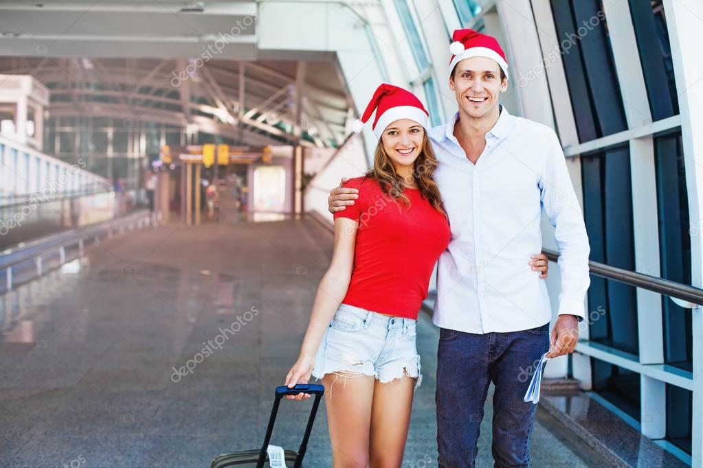 couple in Santa hats in airport with bag