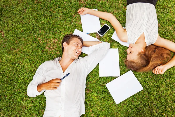 Man and woman with papers and smartphone on grass — Stock Photo, Image