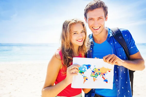 Young couple with map on beach — Stock Photo, Image