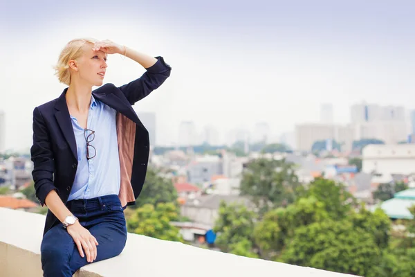 Vrouw op terras met uitzicht op stad — Stockfoto